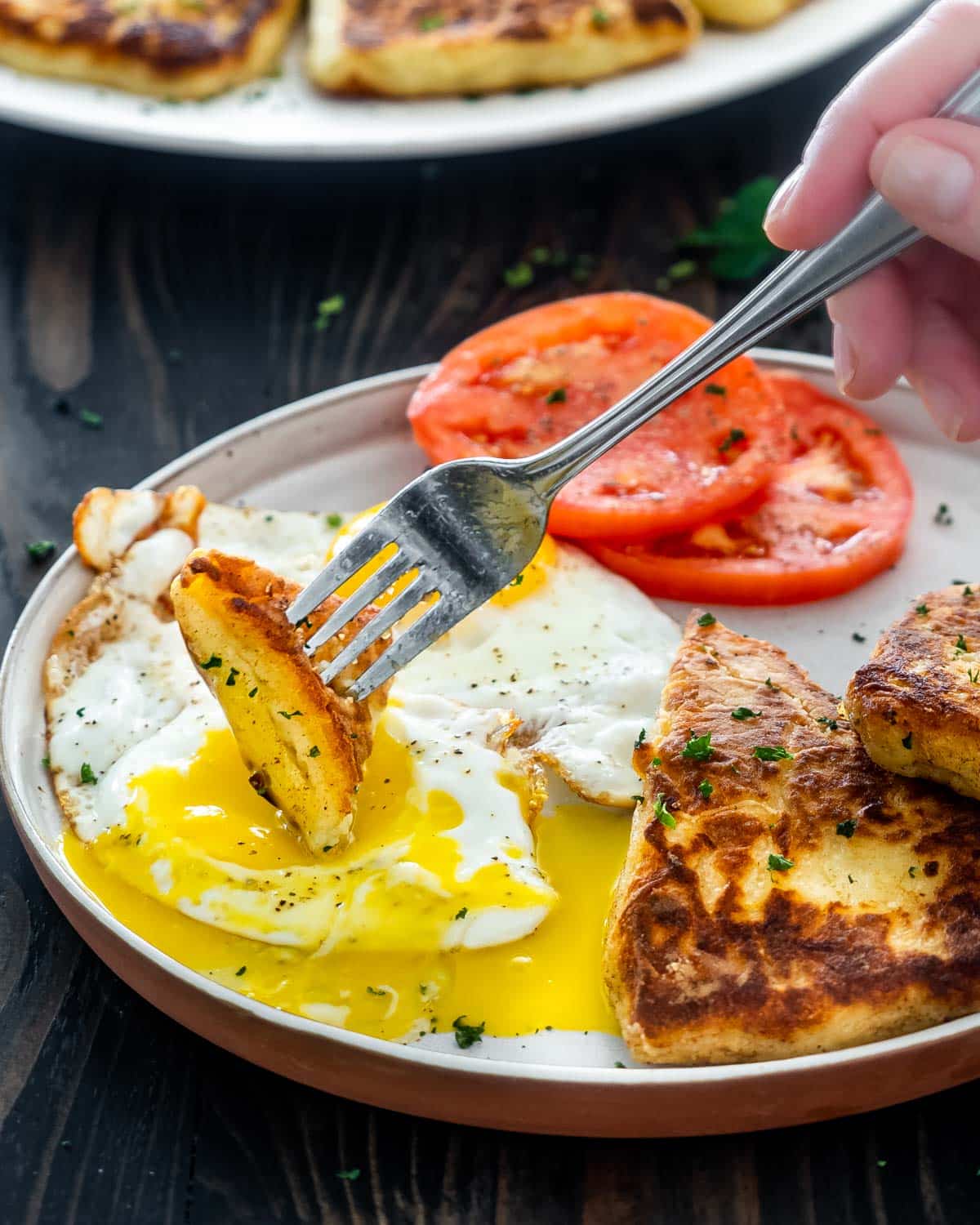 a plate with 2 fried eggs, 2 irish potato cakes and 2 slices of tomatoes.