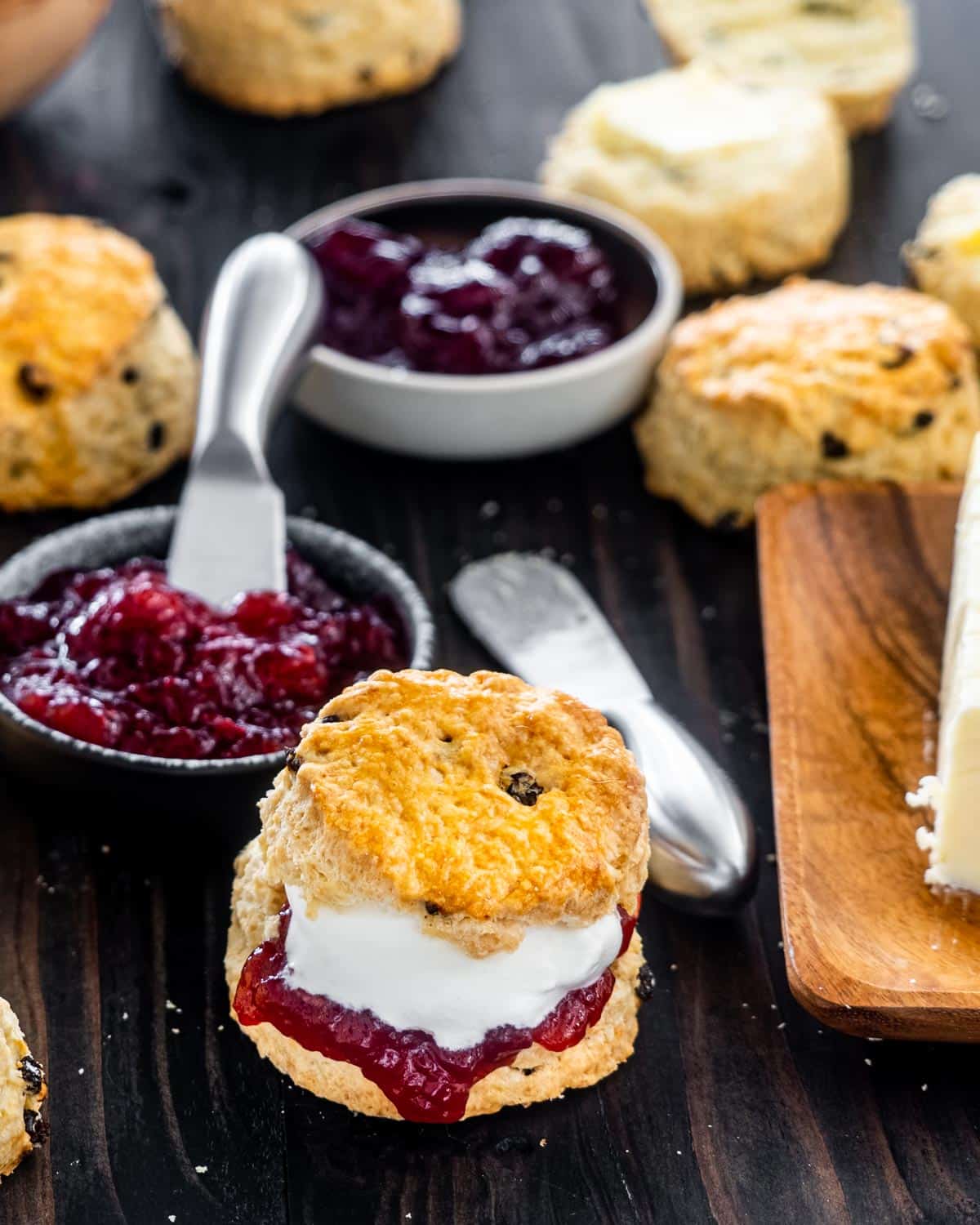an irish scone cut in half with butter, raspberry jam and whipped cream.