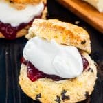 an irish scone cut in half with butter, raspberry jam and whipped cream.
