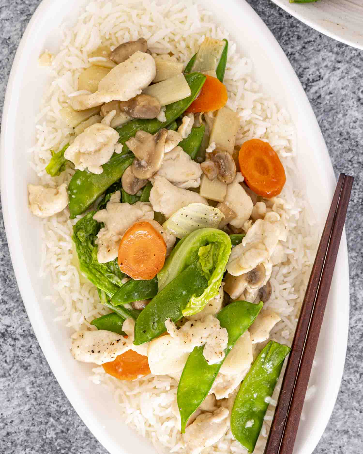 moo goo gai pan over rice on a white plate.