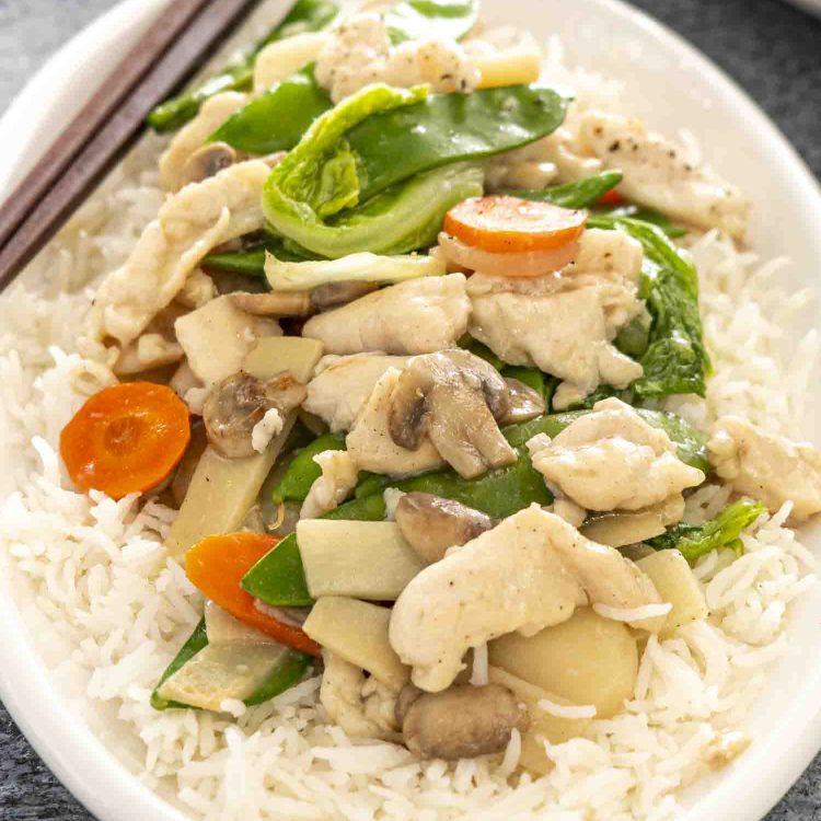 moo goo gai pan over rice on a white plate.