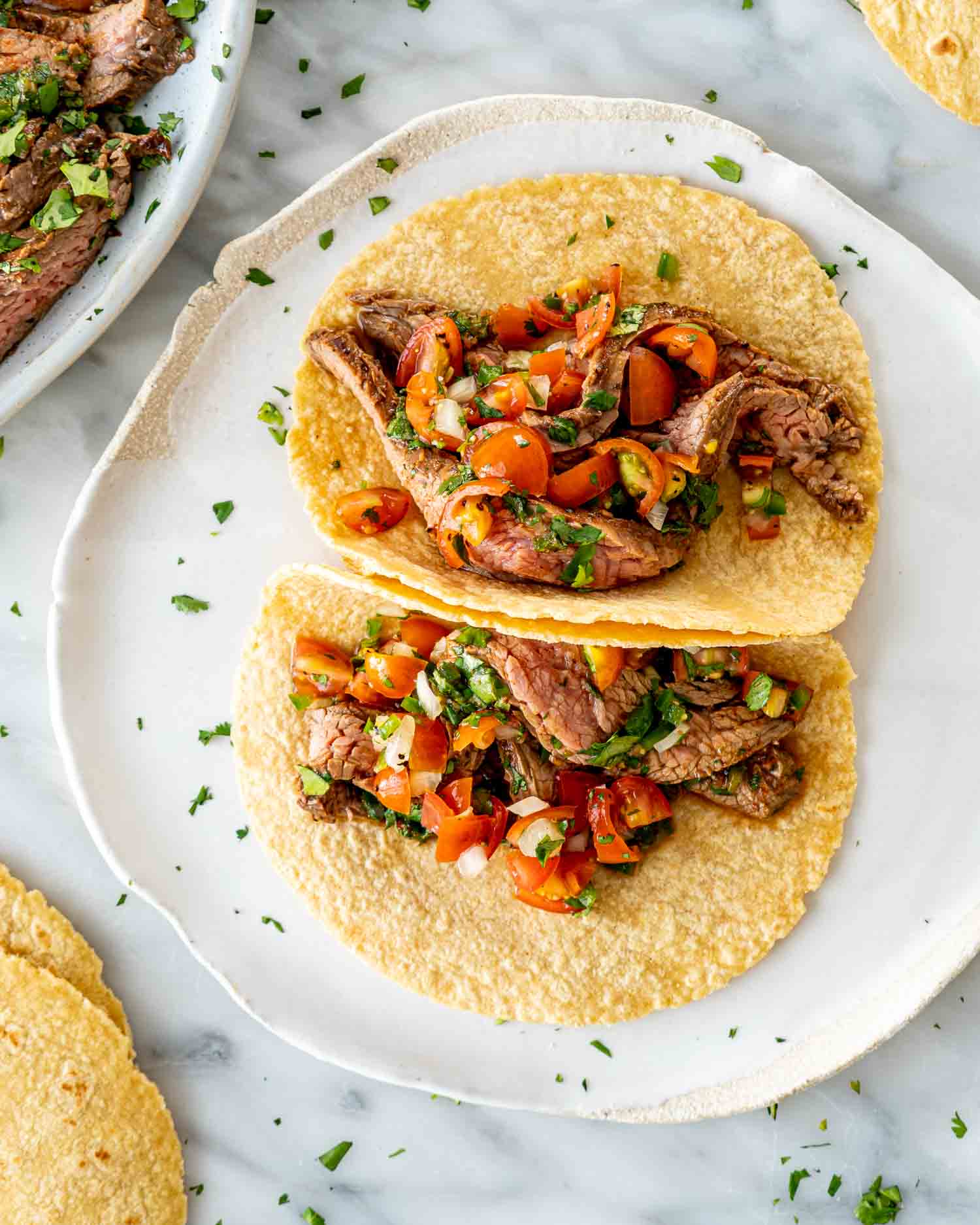 two tacos with carne asada on a plate.