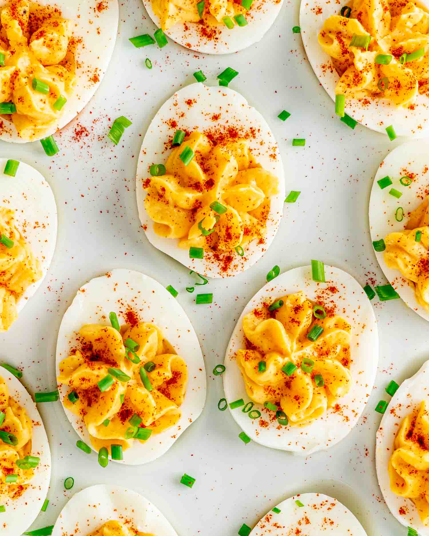 deviled eggs on a serving platter garnished with paprika and chives.