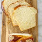 4 Slices of Easter bread being cut from the loaf on a wooden cutting board.