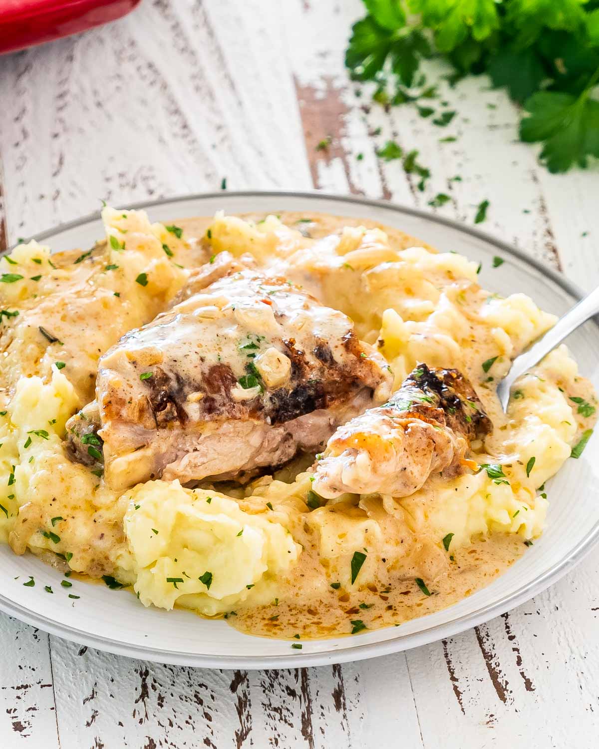 a chicken thigh with gravy over a bed of mashed potatoes.