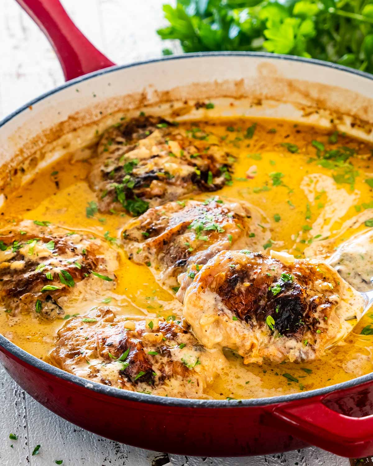 smothered chicken with gravy in a skillet garnished with parsley.