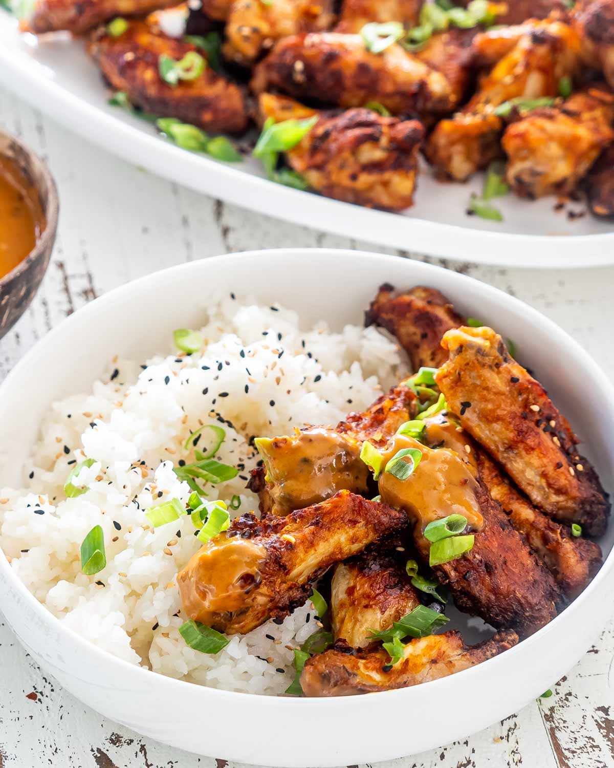 thai chicken wings with rice in a white bowl.