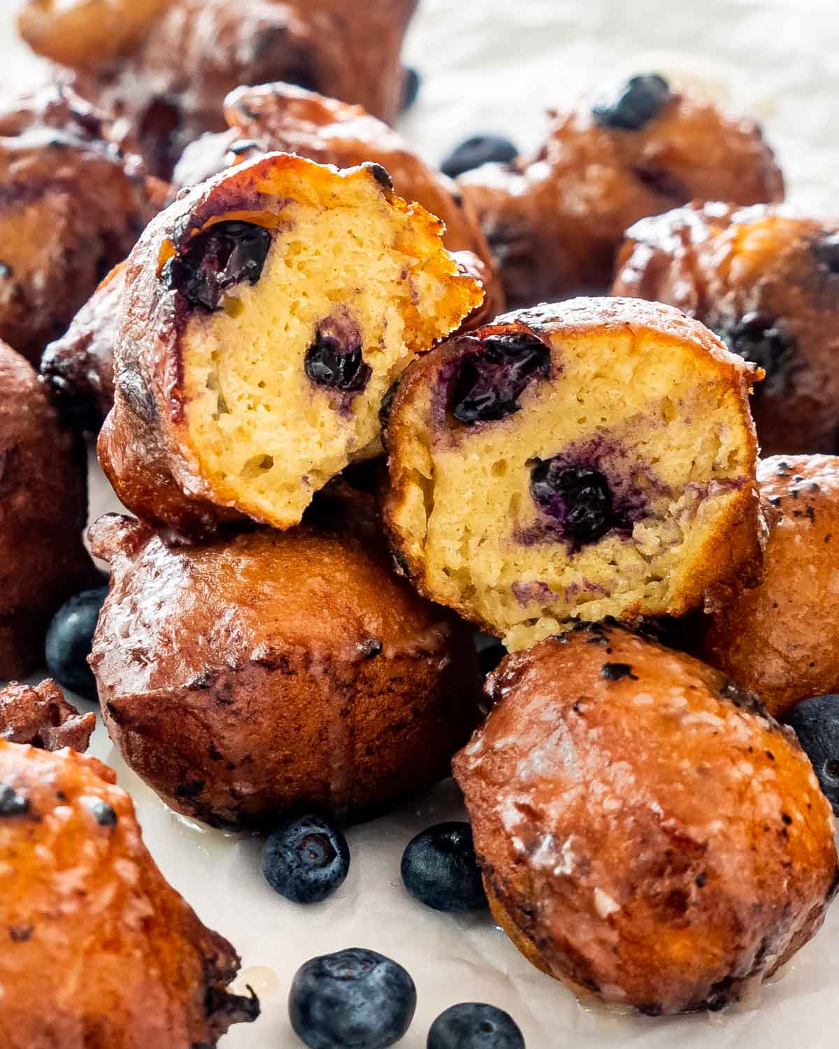 a bunch of blueberry fritters with one cut in half.