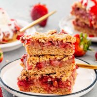 three pieces of strawberry rhubarb bars on a white plate.