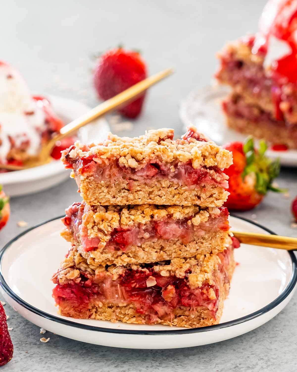 three pieces of strawberry rhubarb bars on a white plate.