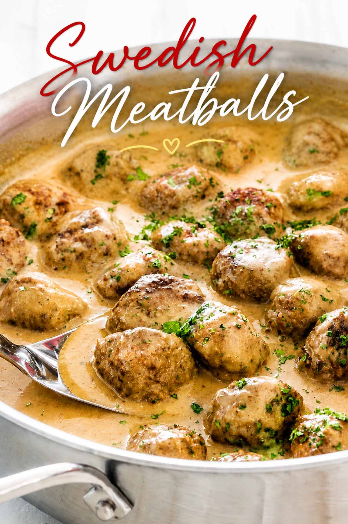A silver spoon lifting beef meatballs in a creamy gravy within a skillet with red script text overlaying the image.