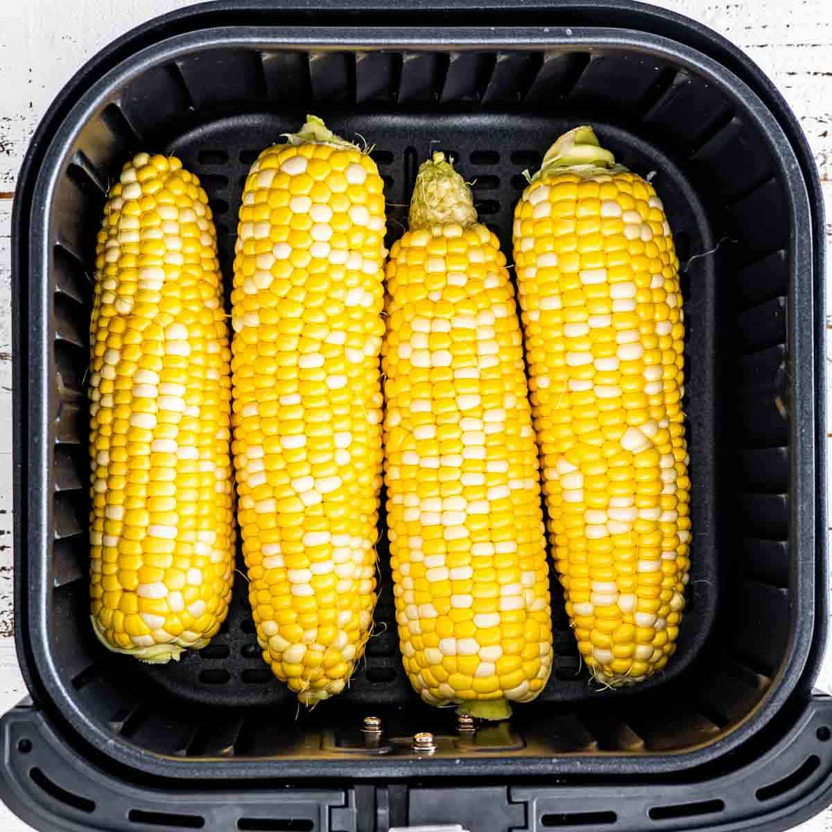 corn on the cob in an air fryer basket.