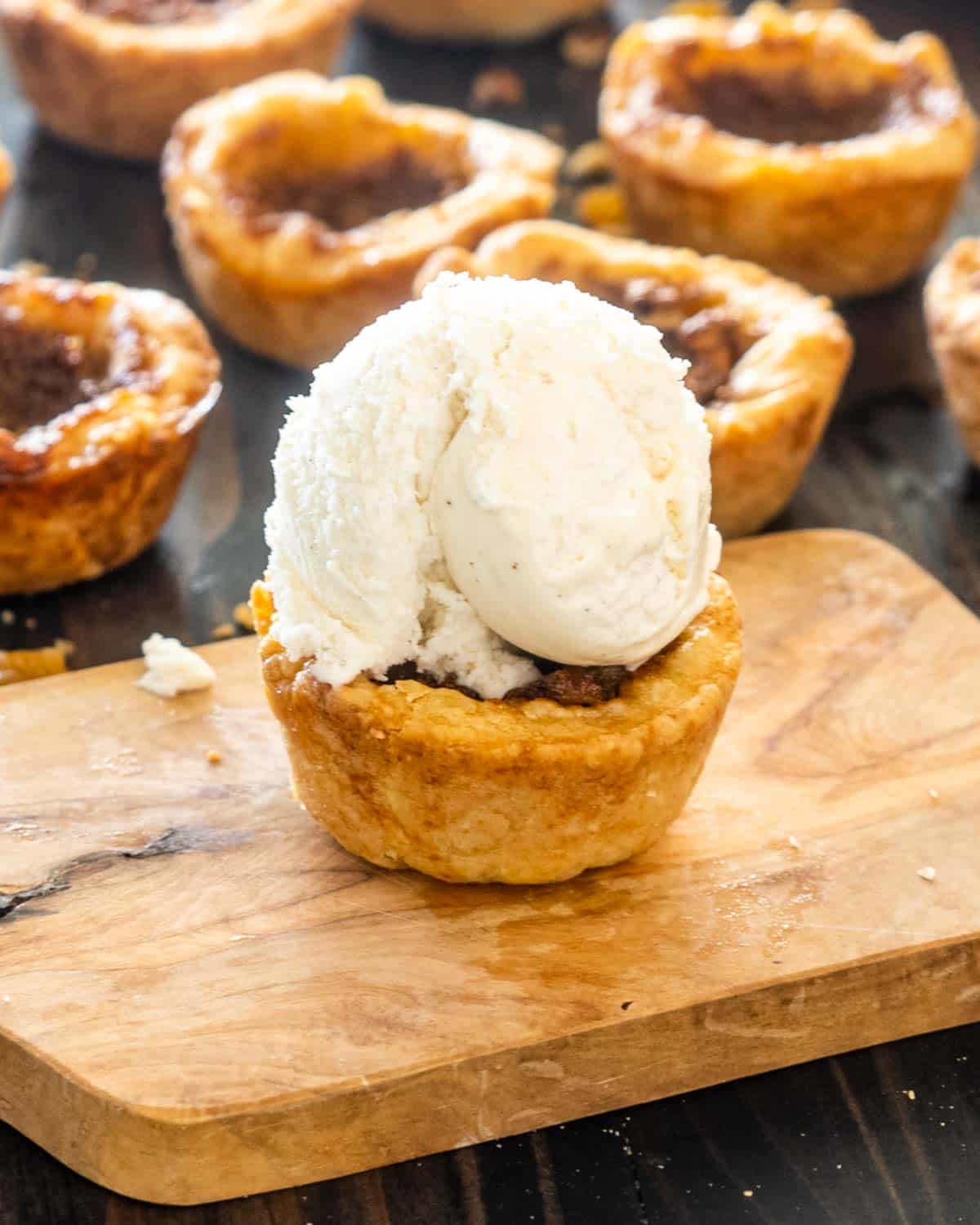 a butter tart on a cutting board with a scoop of ice cream on top.