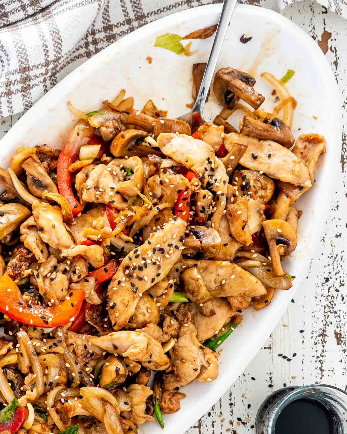 chicken mushroom stir fry on a white platter with serving spoon.