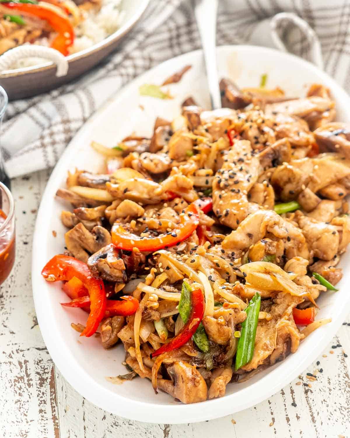 chicken mushroom stir fry on a white platter with serving spoon.