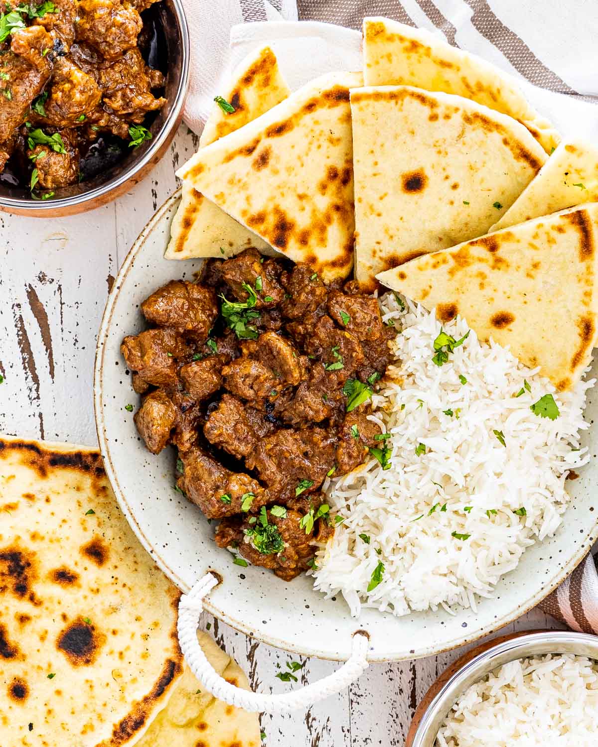 lamb korma with naan and rice in a dish.