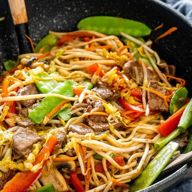 beef lo mein in a black wok.