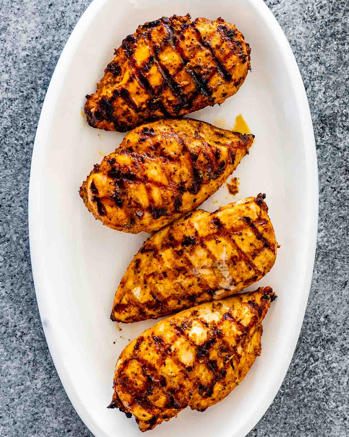 grilled chicken breast on a white serving platter.