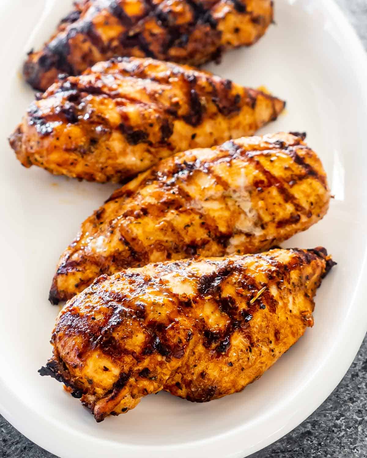 grilled chicken breast on a white serving platter.