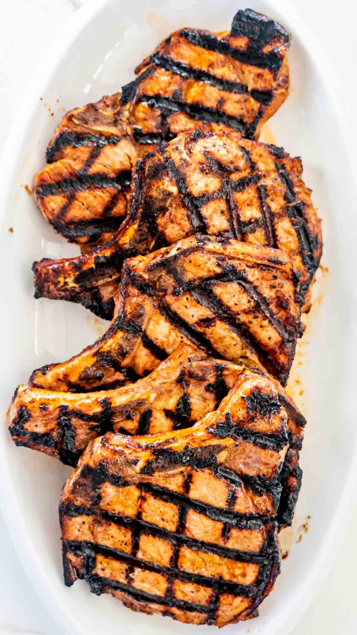grilled pork chops on a white serving platter.