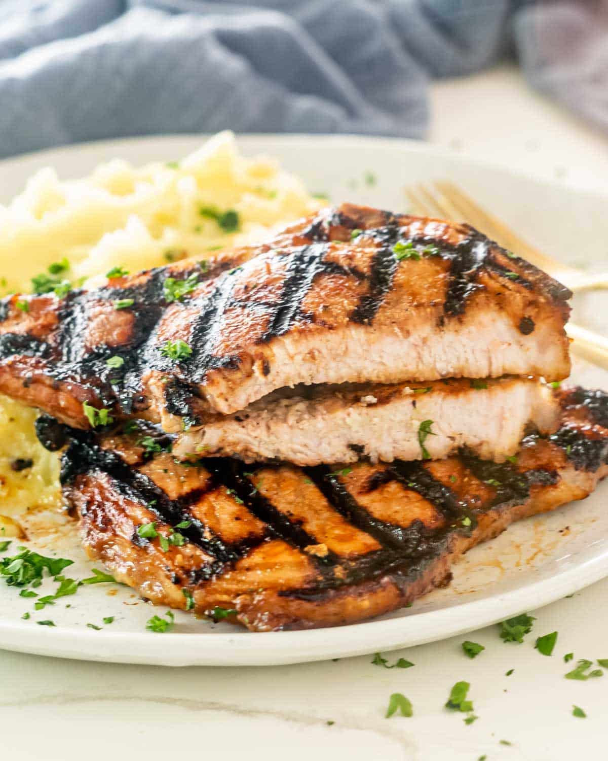 2 grilled pork chops with mashed potatoes on a plate.