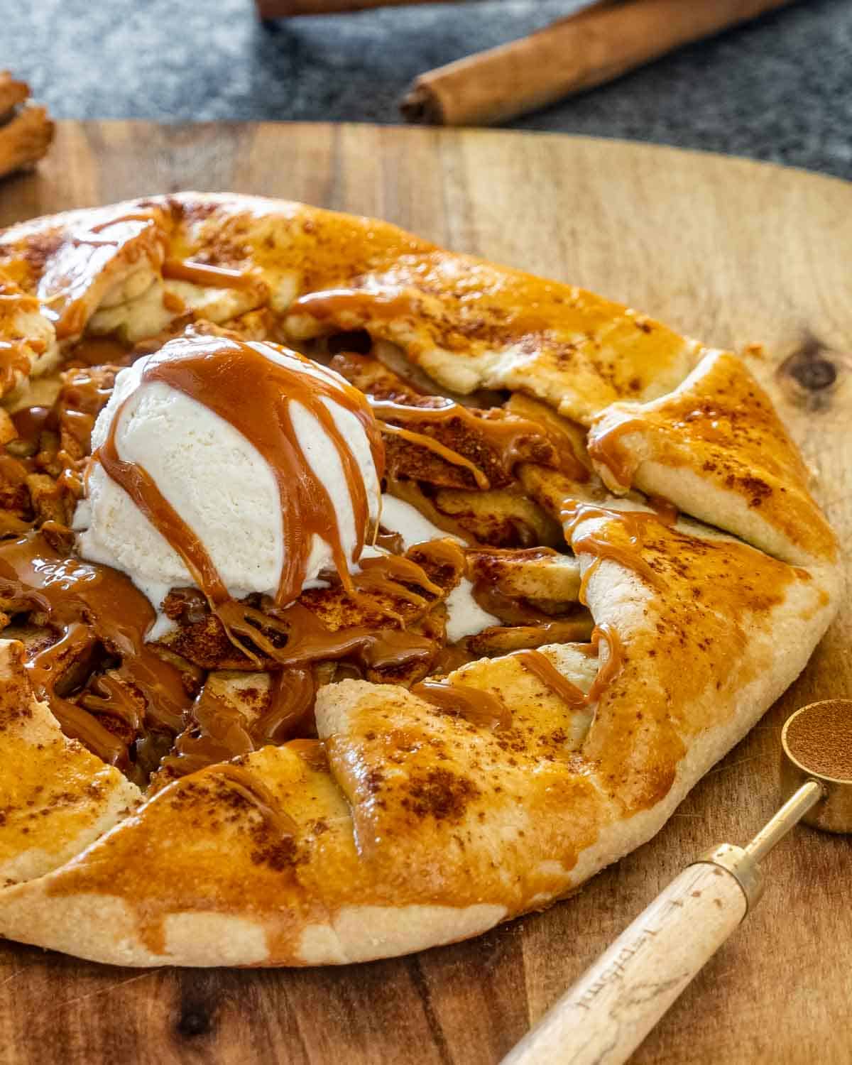 an apple galette with a scoop of ice cream and caramel topping.