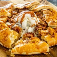 an apple galette with a scoop of ice cream and caramel topping with a slice cut out.