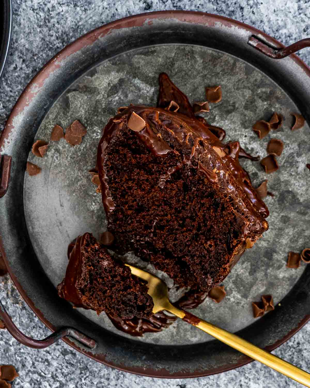 a slice of chocolate bundt cake with chocolate ganache and chocolate shavings.
