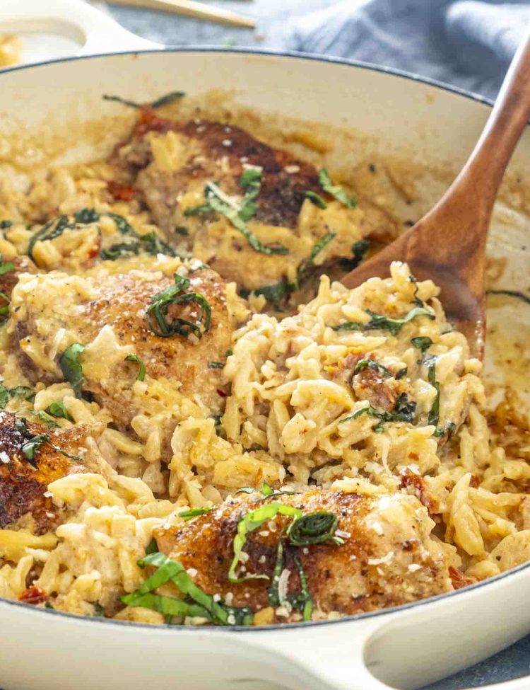 one pot chicken an orzo in a braiser, garnished with basil.