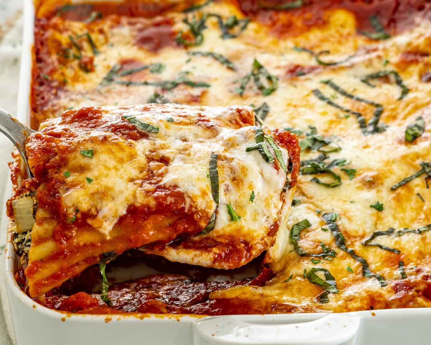 side view shot of a stuffed manicotti being lifted from the pan.