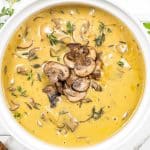 cream of mushroom soup garnished with sauteed mushrooms in a white bowl.