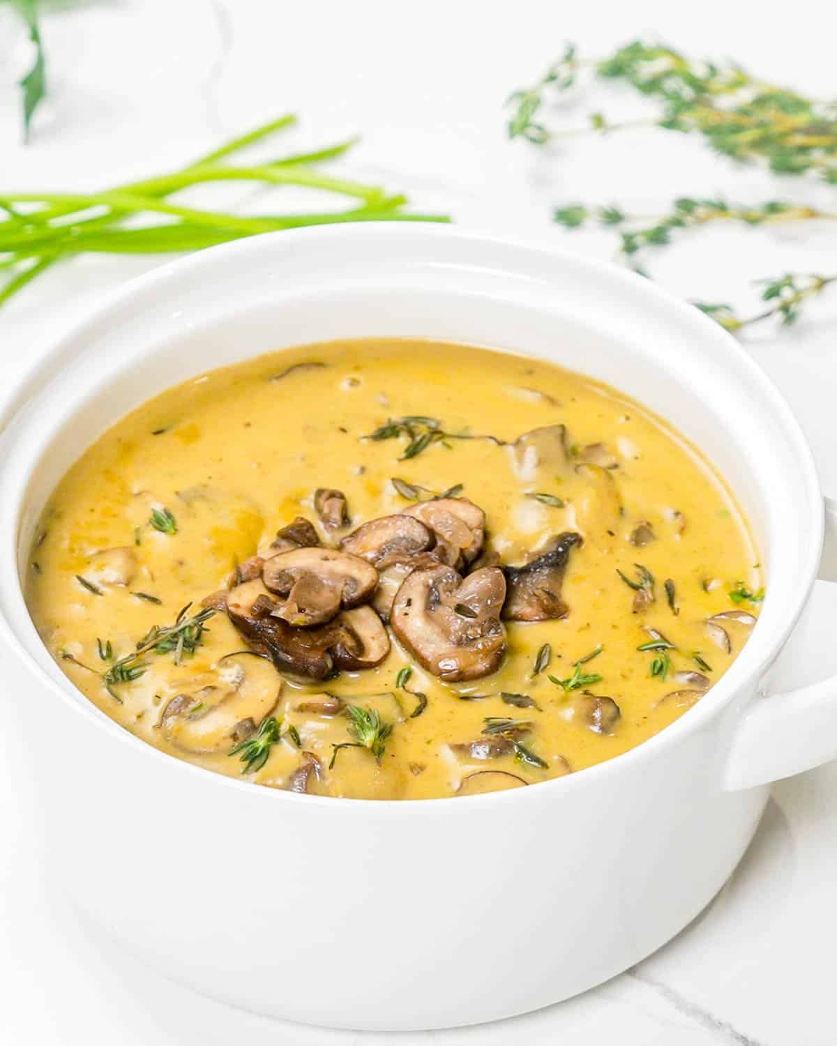 cream of mushroom soup garnished with sauteed mushrooms in a white bowl.