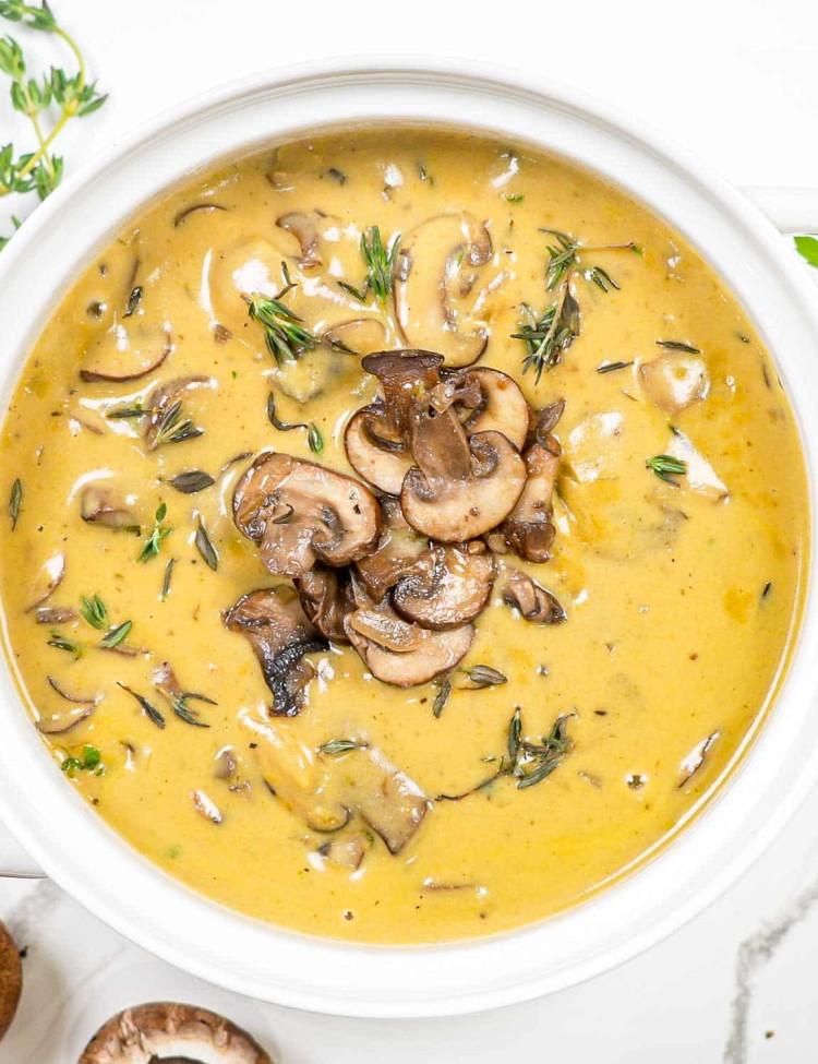 cream of mushroom soup garnished with sauteed mushrooms in a white bowl.