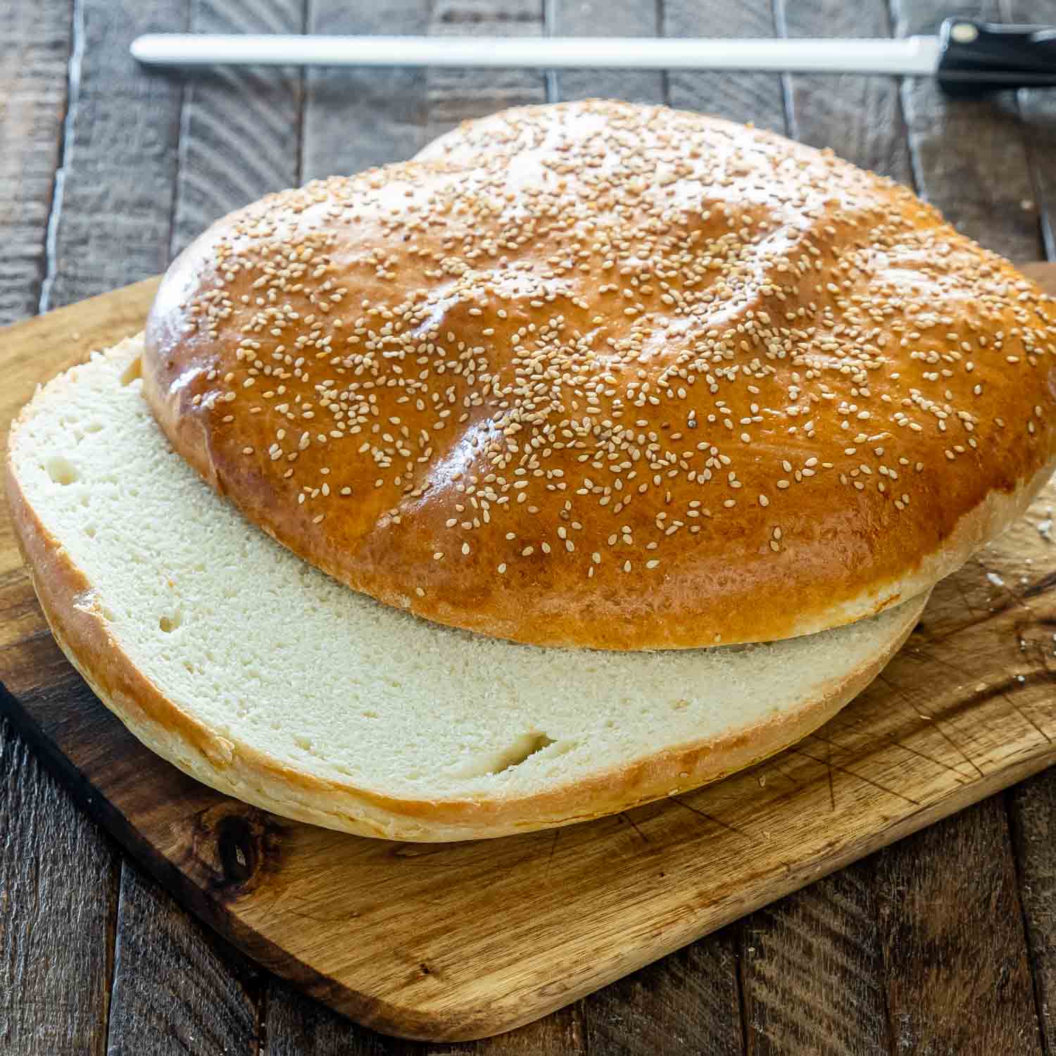 muffuletta bread cut in half on a cutting board.