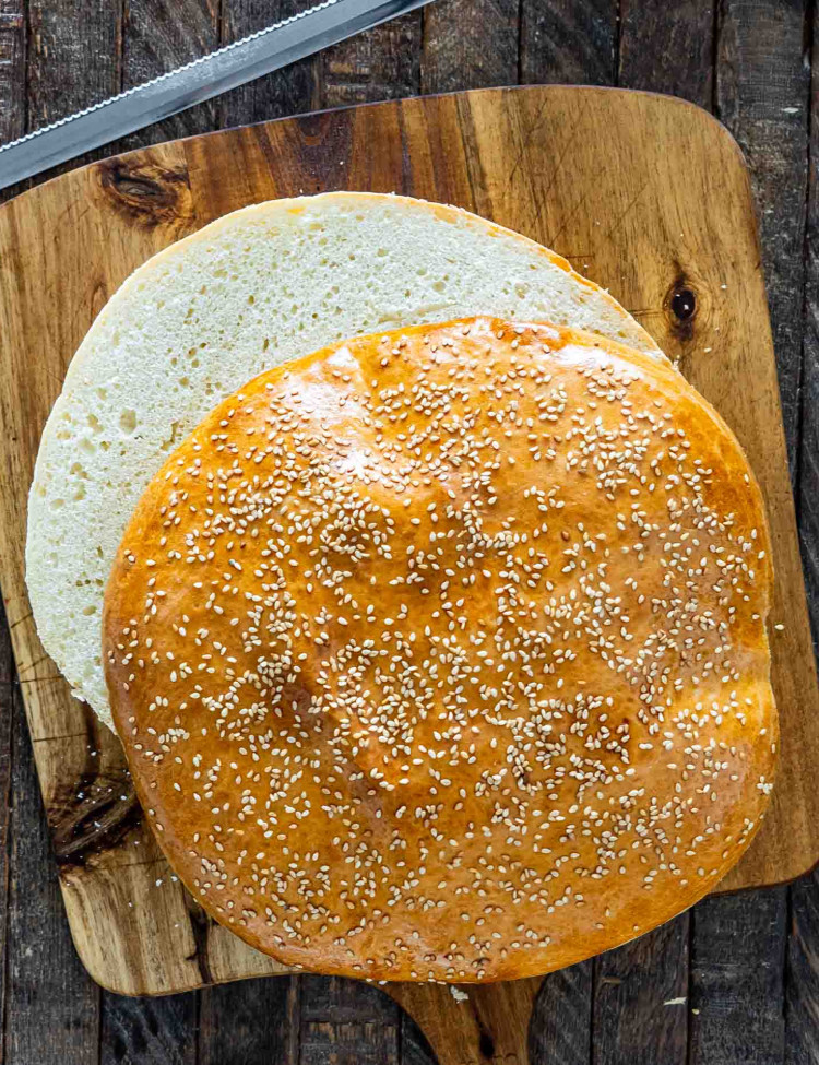 muffuletta bread cut in half on a cutting board.
