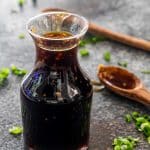 teriyaki sauce in a bottle with a tablespoon with teriyaki sauce.
