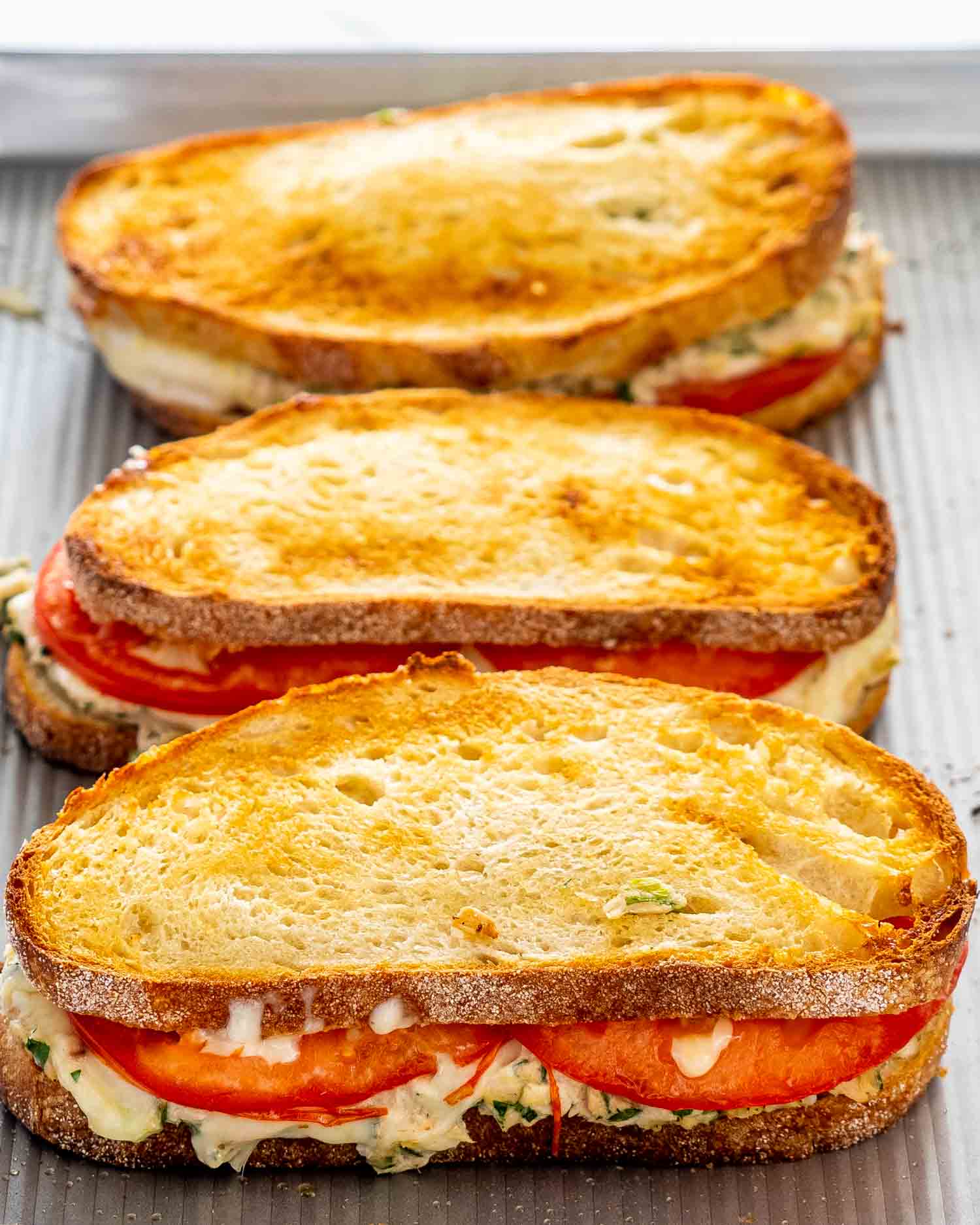 tuna melt sandwiches fresh out of the oven on a baking sheet.