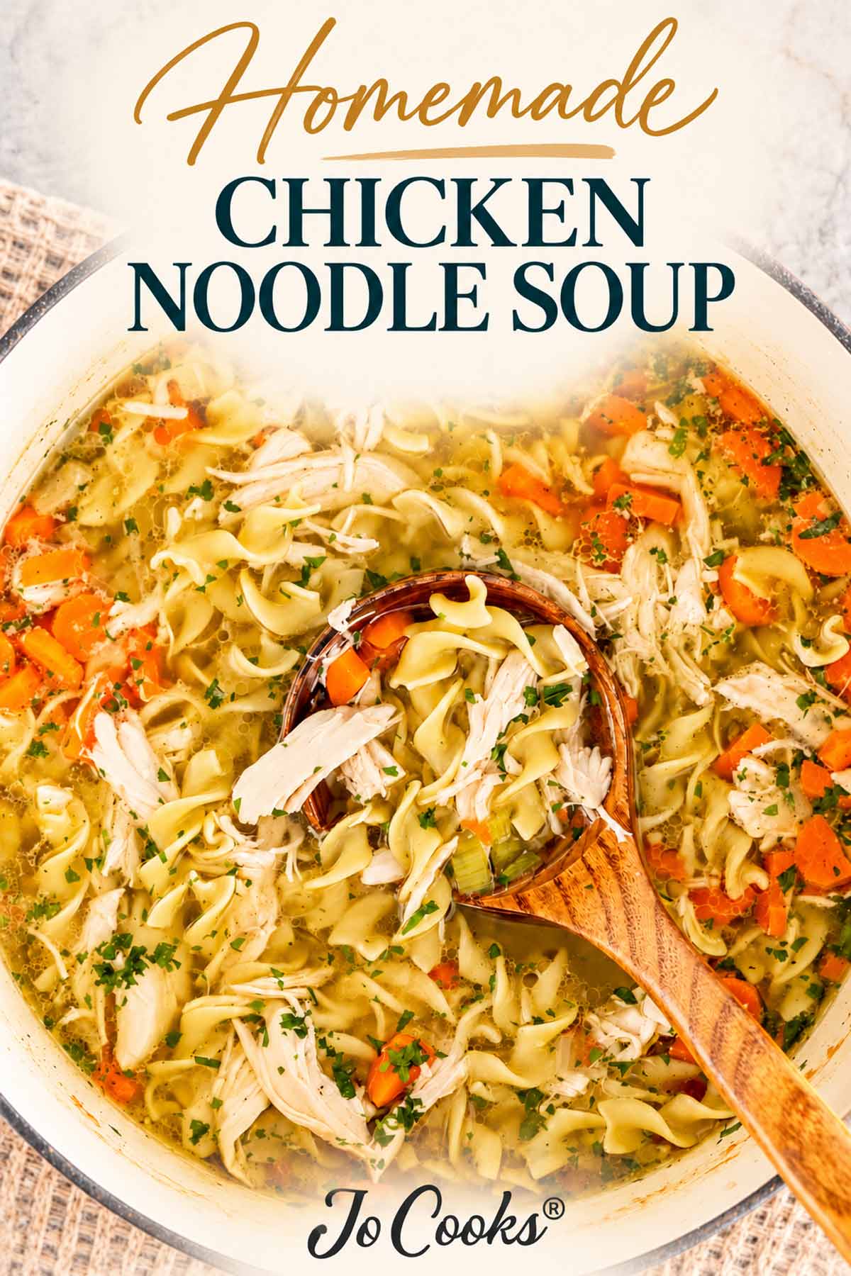 Overhead view of homemade chicken noodle soup with a wooden ladle, topped with an elegant recipe title and Jo Cooks logo.