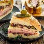 a quarter of muffuletta sandwich on a plate.