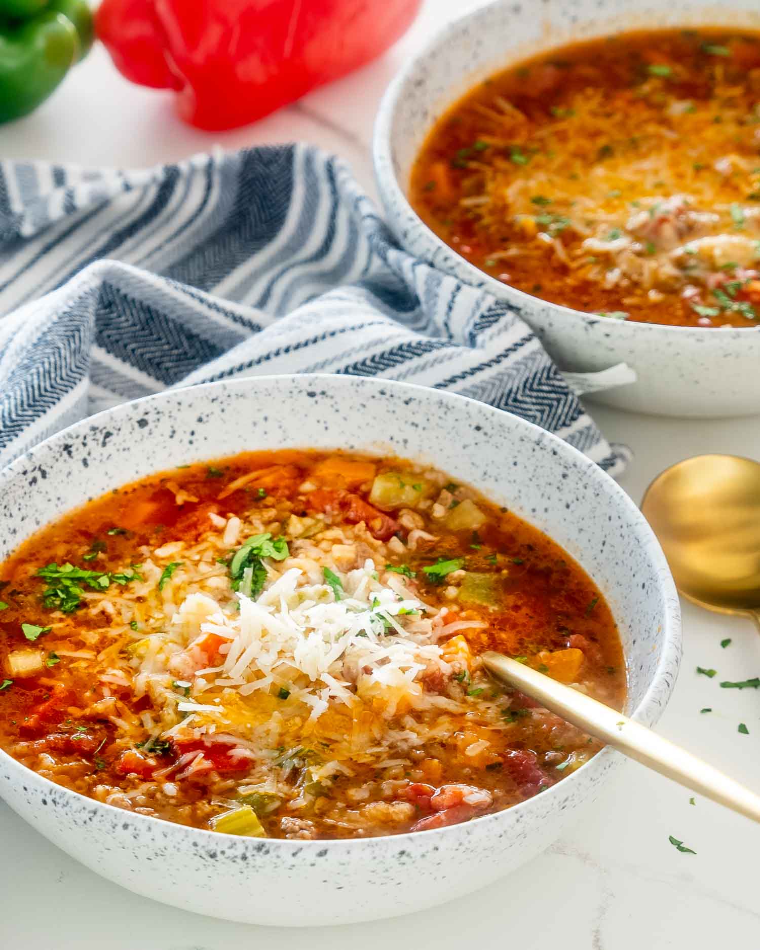 stuffed pepper soup in a white bowl with parmesan cheese on top.