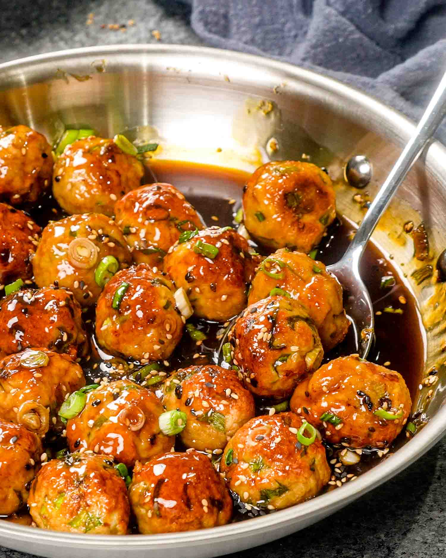 teriyaki chicken meatballs in a skillet garnished with green onions.