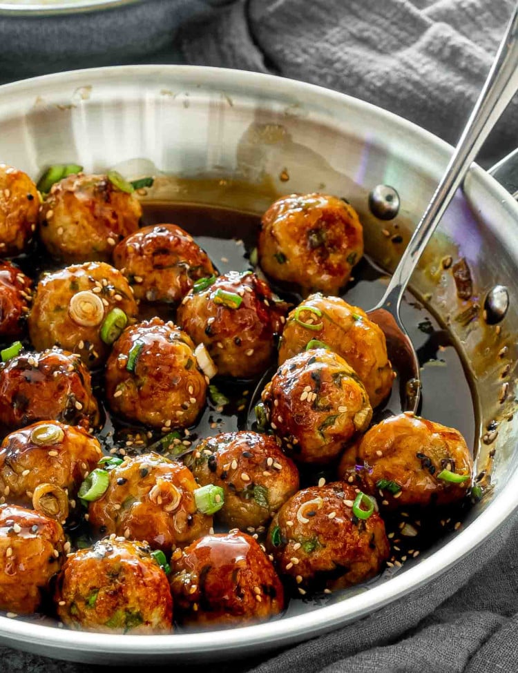 teriyaki chicken meatballs in a skillet garnished with green onions.