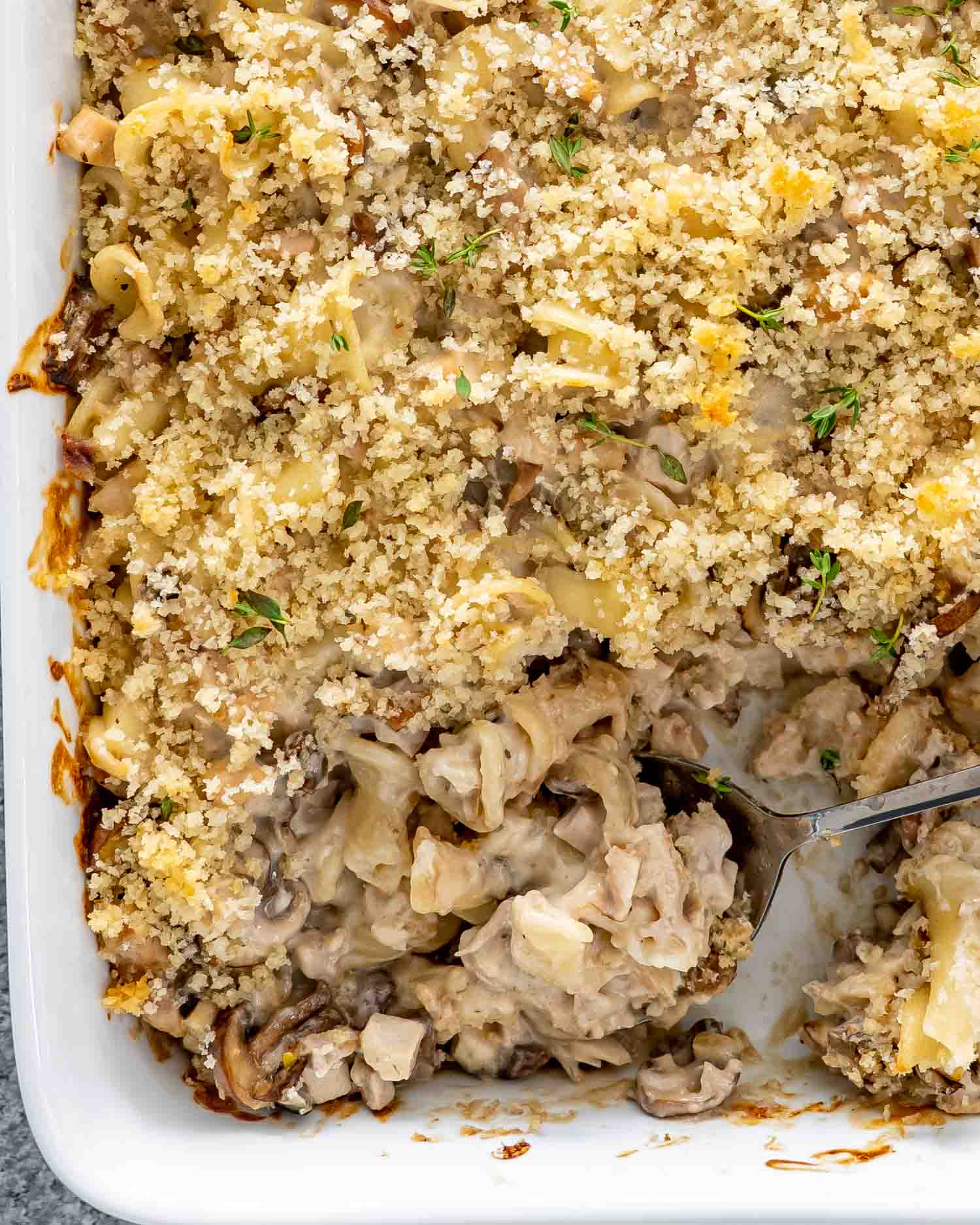 turkey noodle casserole in a white casserole dish with a serving spoon inside.