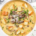 philly cheesesteak soup in a white bowl topped with croutons.