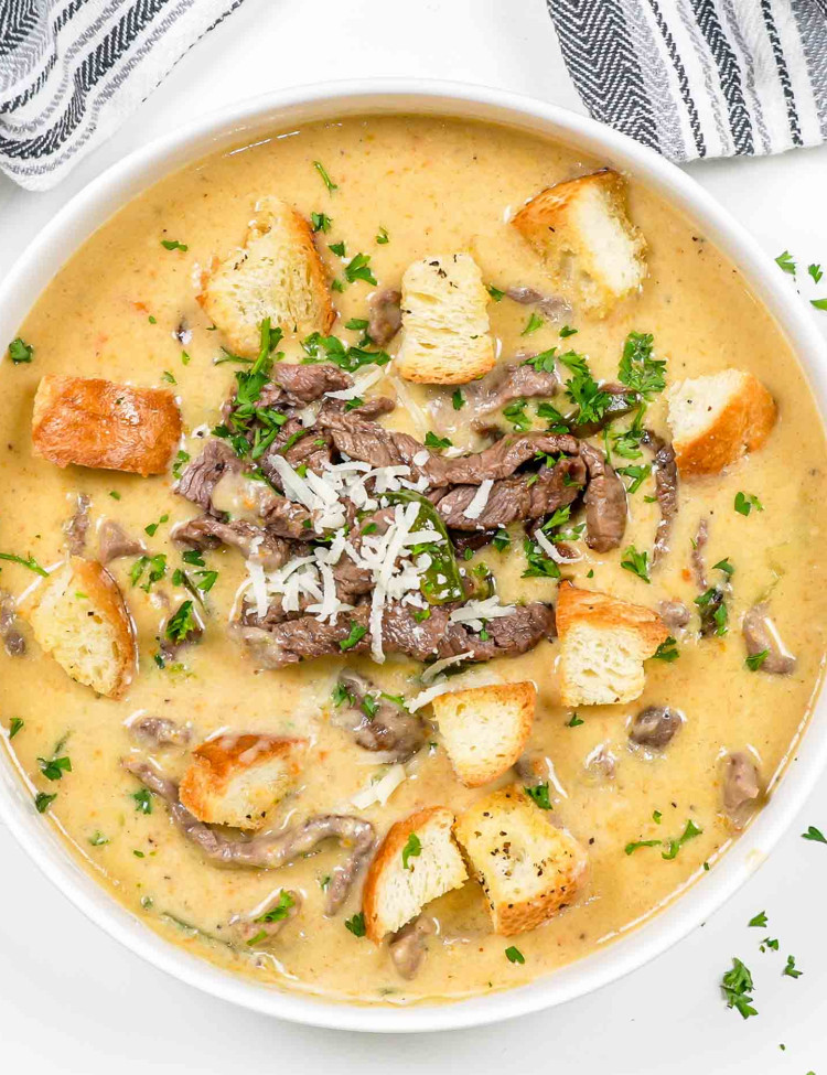 philly cheesesteak soup in a white bowl topped with croutons.