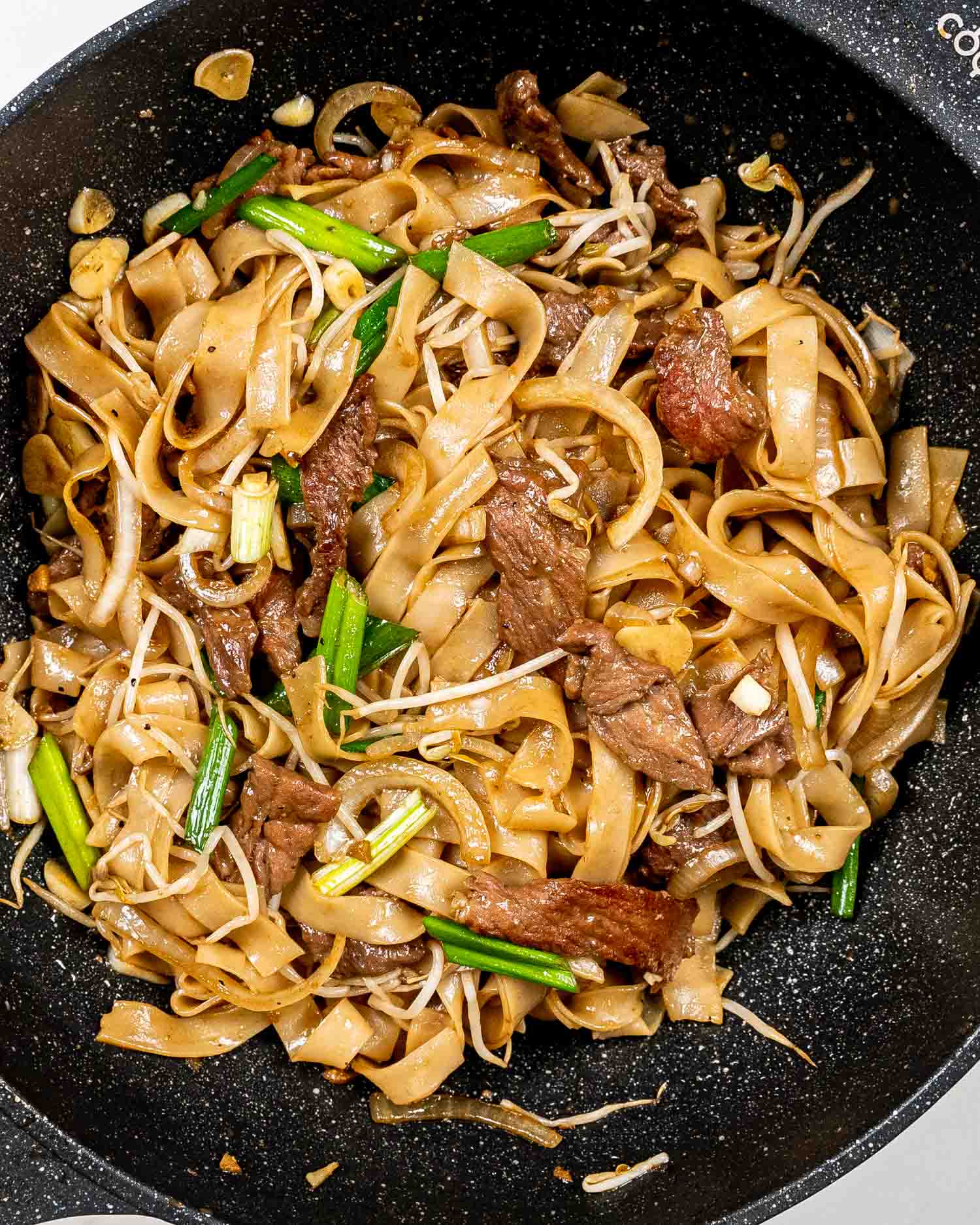 beef chow fun in a black wok.