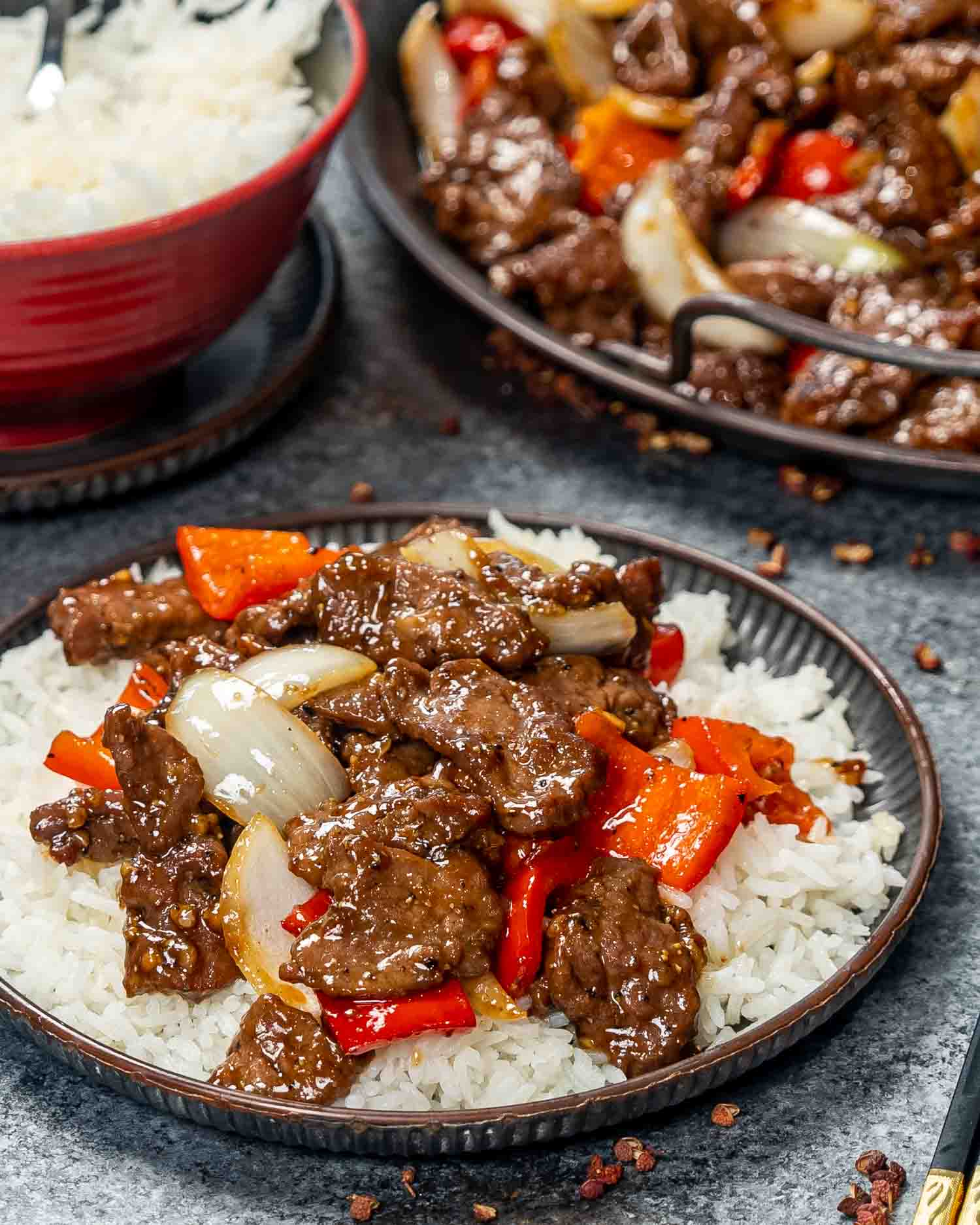 a serving of black pepper beef over a bed of rice.