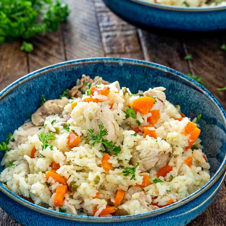 chicken and rice made in the instant pot in a blue bowl garnished with parsley.