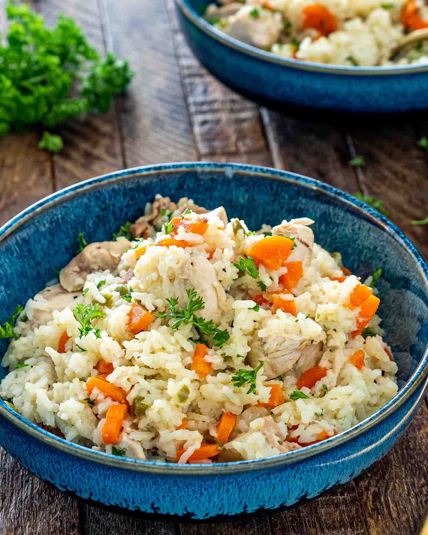chicken and rice made in the instant pot in a blue bowl garnished with parsley.