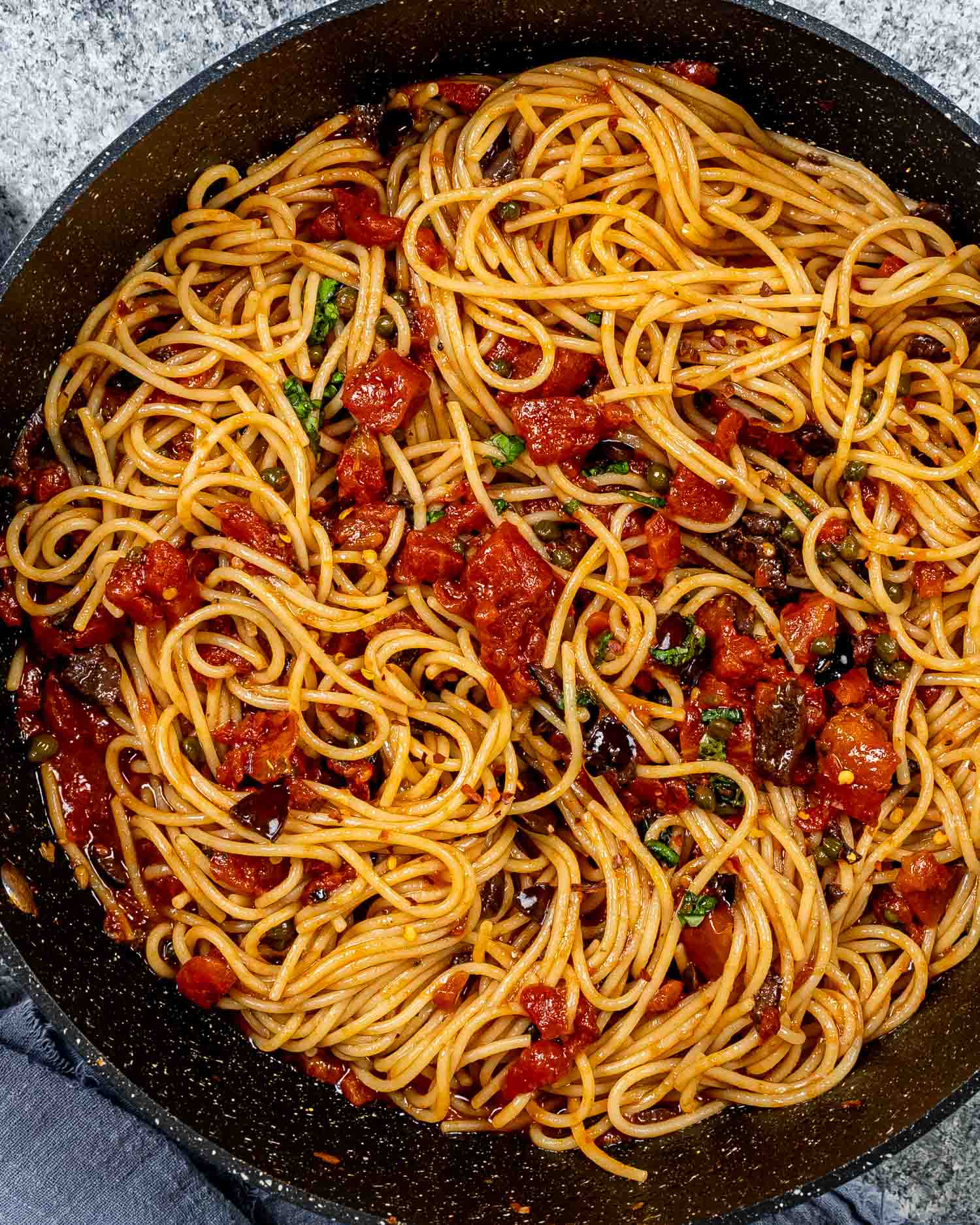 freshly made pasta puttanesca in a blue skillet.